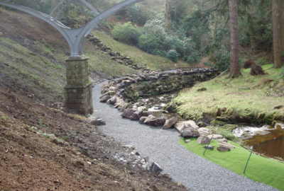River next to a patch under a bridge with rock barrier