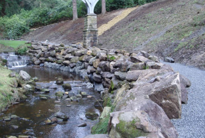 Rocky path going past river and under bridge