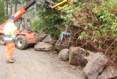 Crane moving rock on side of road